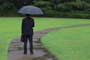 雨の中たたずむビジネスパーソン