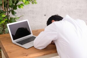 ノートパソコンの前で居眠りをしている人